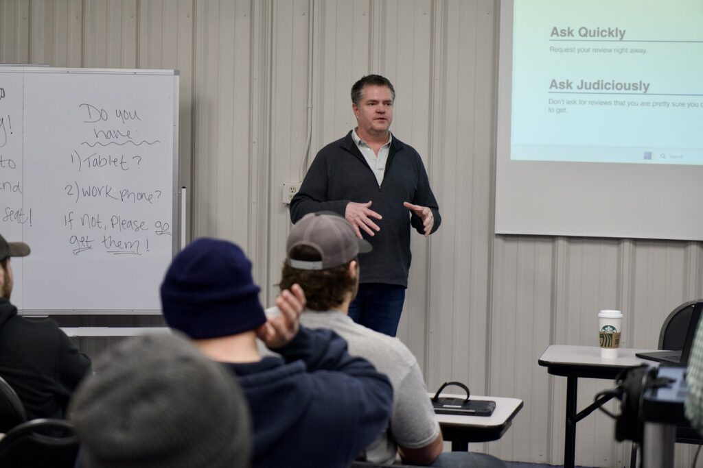 Brett Lewis training a room of technicians on review request best practices, with an Ask Quickly slide on screen